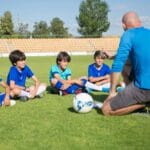 Dzieci podczas treningu piłki nożnej na boisku w słoneczny dzień