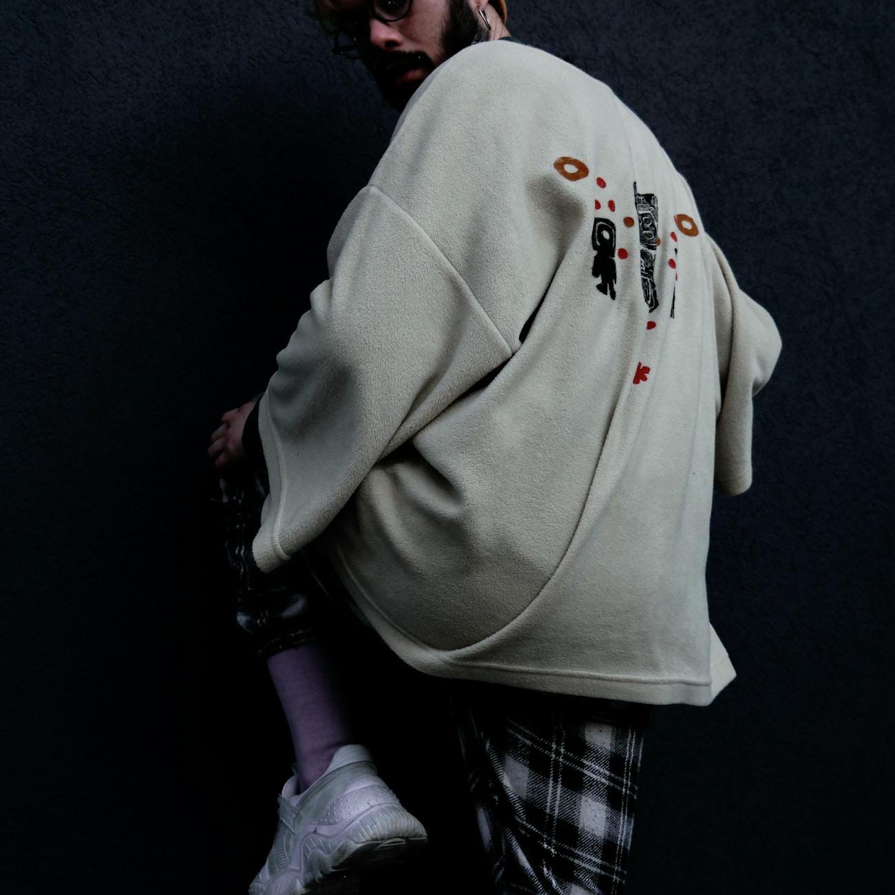 Jak nosić oversize w elegancki sposób – praktyczny poradnik na co dzień Mężczyzna w oversize swetrze i białych sneakersach na ciemnym tle miasta