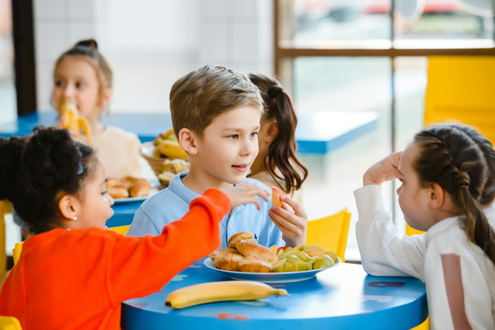 Dobre nawyki żywieniowe dzieci w Gorzowie: jak nie ulec pokusom fast foodów Dzieci przy stole jedzą wspólny posiłek w przyjaznej atmosferze