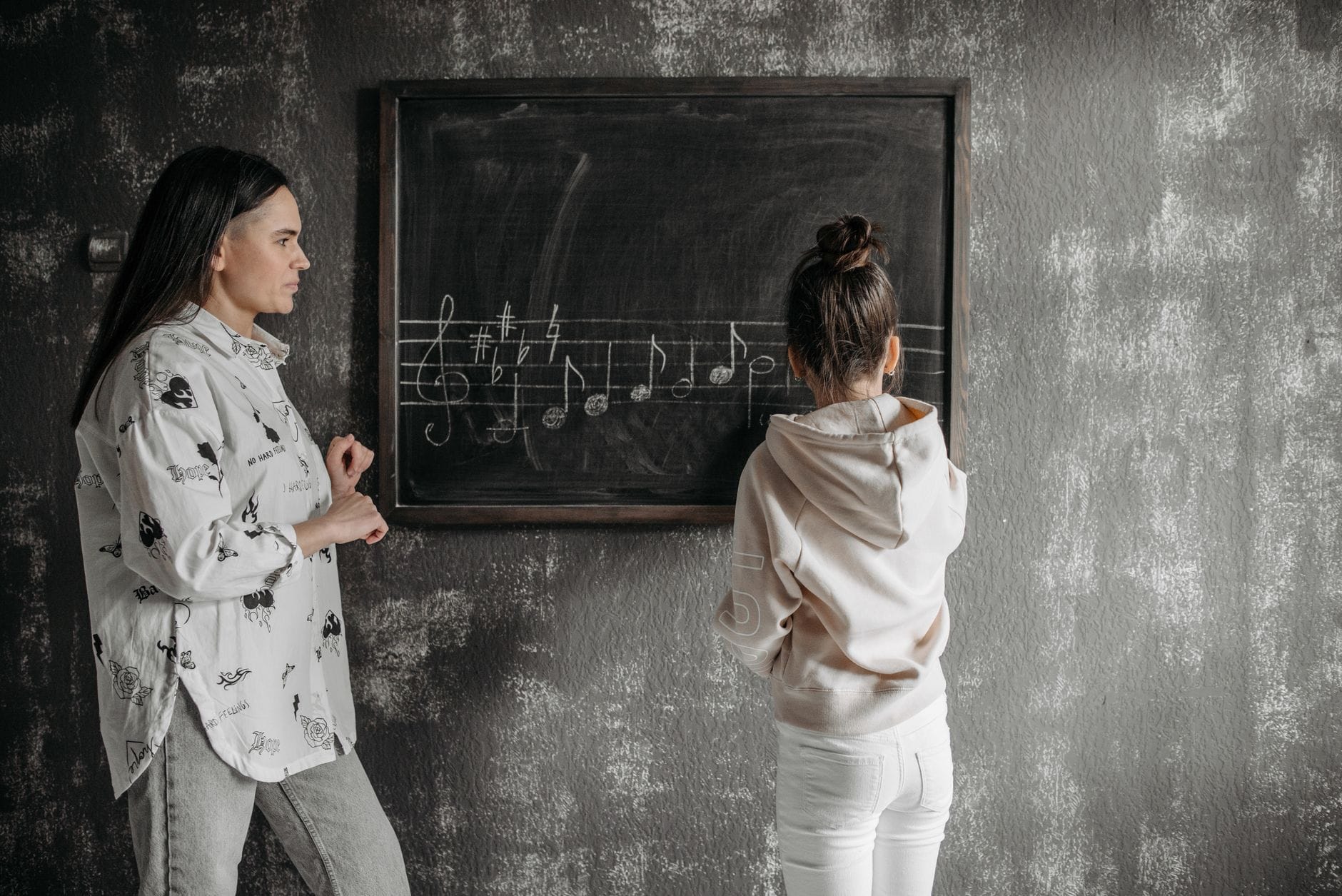 Mama uczy córkę nut przy tablicy podczas lekcji muzyki