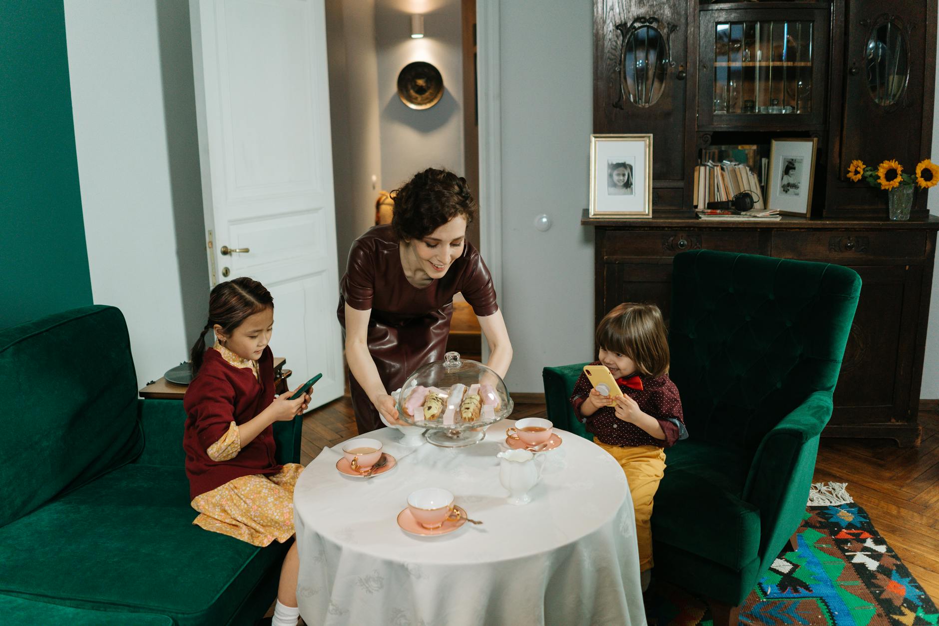 Niania podaje dzieciom ciasto w przytulnym salonie Niania podaje dzieciom ciasto w przytulnym salonie