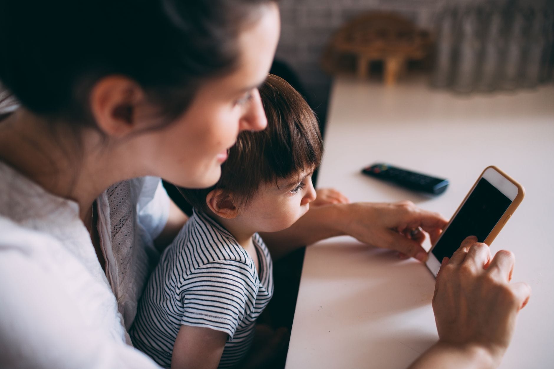 Mama i dziecko razem korzystają ze smartfona w domu Mama i dziecko razem korzystają ze smartfona w domu